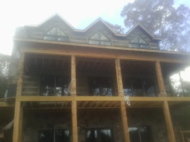 Dormers and porch framing on a large log home under construction — Roof Coating work by our crew in Henderson